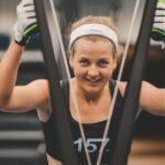 Skidåkaren Carolina Hedenström som befinner sig på gymmet och håller i handtagen till SkiErg medan hon tittar in i kameran.